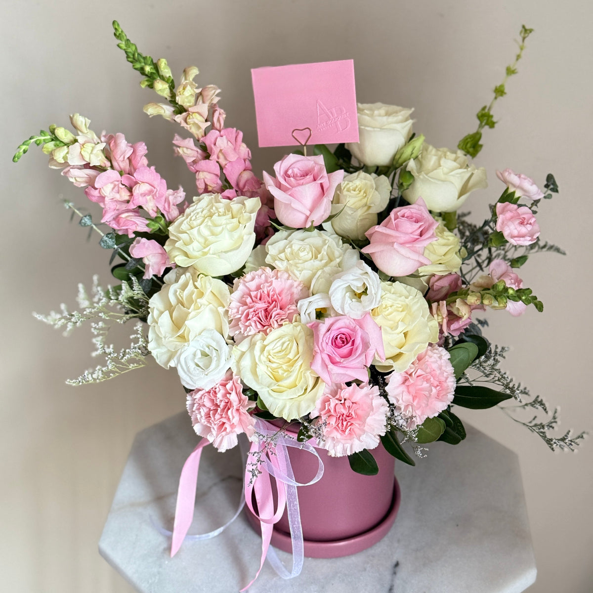 Arrangement Bouquet of pink and white flowers in a pink-purple pot on a marble surface with a light gray background