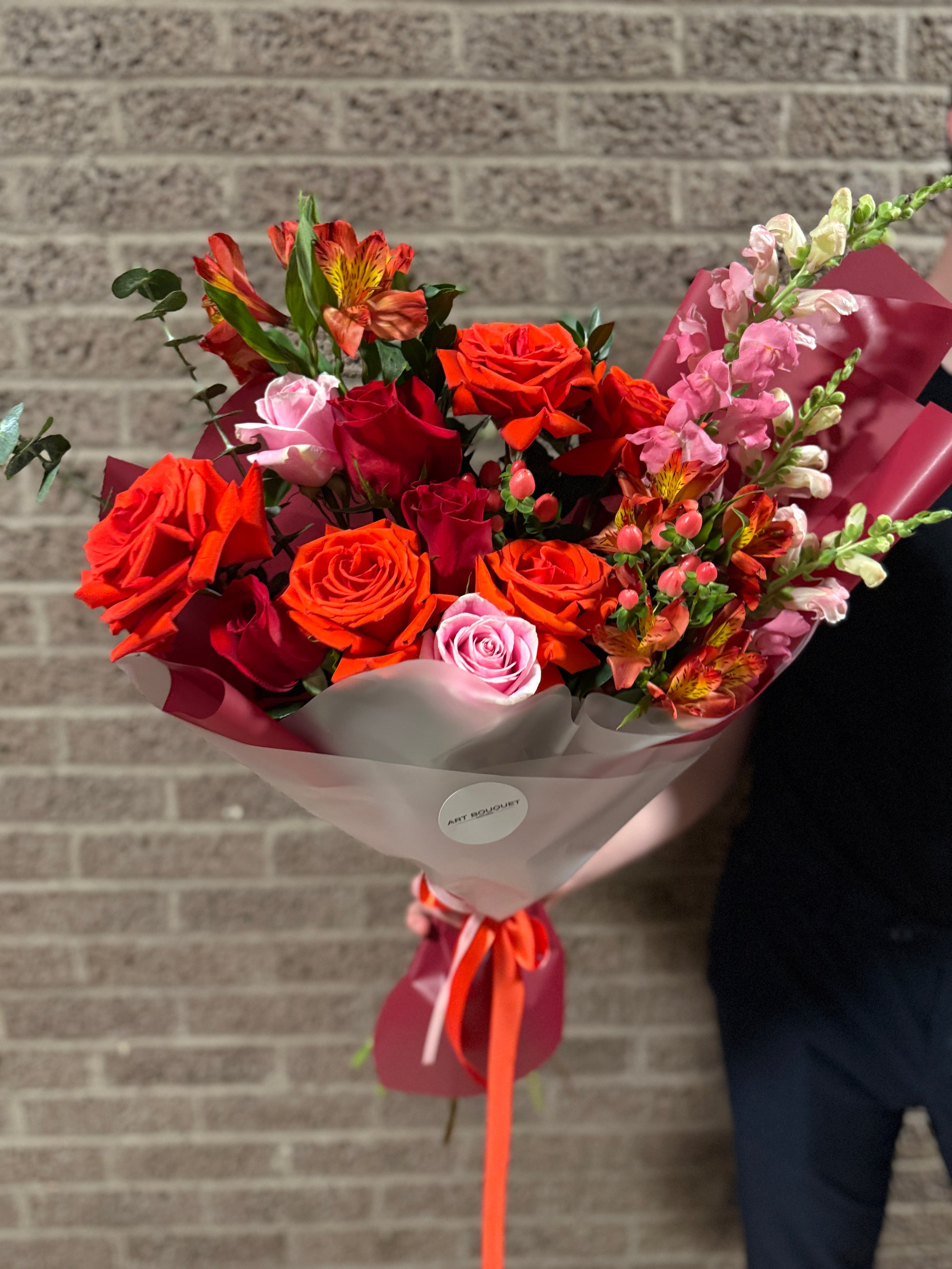 Vibrant mixed flower bouquet with red and orange roses, pink roses, alstroemeria, and snapdragons, for flower delivery in Montreal. Fresh red roses, premium flowers. livraison de fleurs Montréal