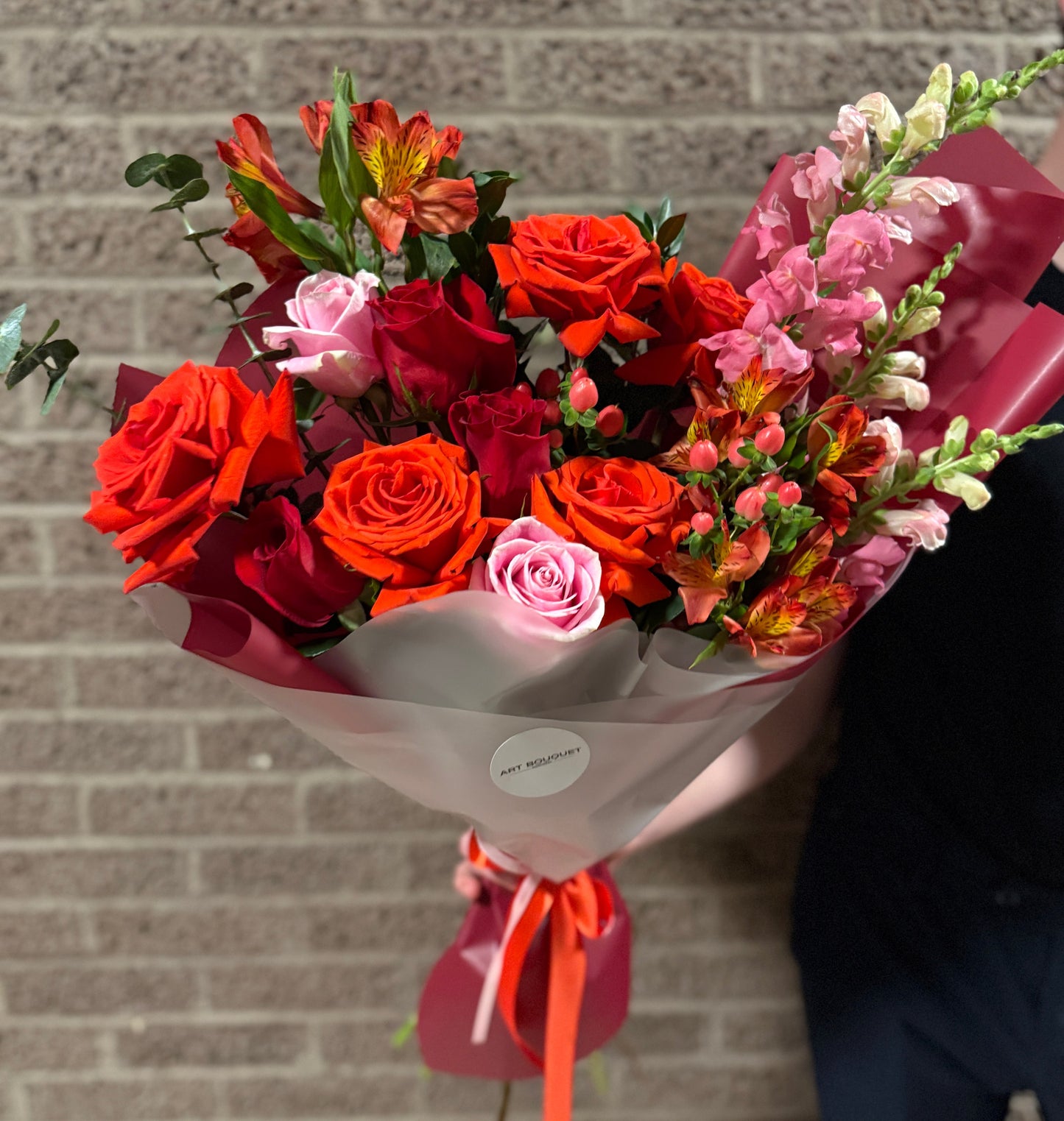 Vibrant mixed flower bouquet with red and orange roses, pink roses, alstroemeria, and snapdragons, for flower delivery in Montreal. Fresh red roses, premium flowers. livraison de fleurs Montréal