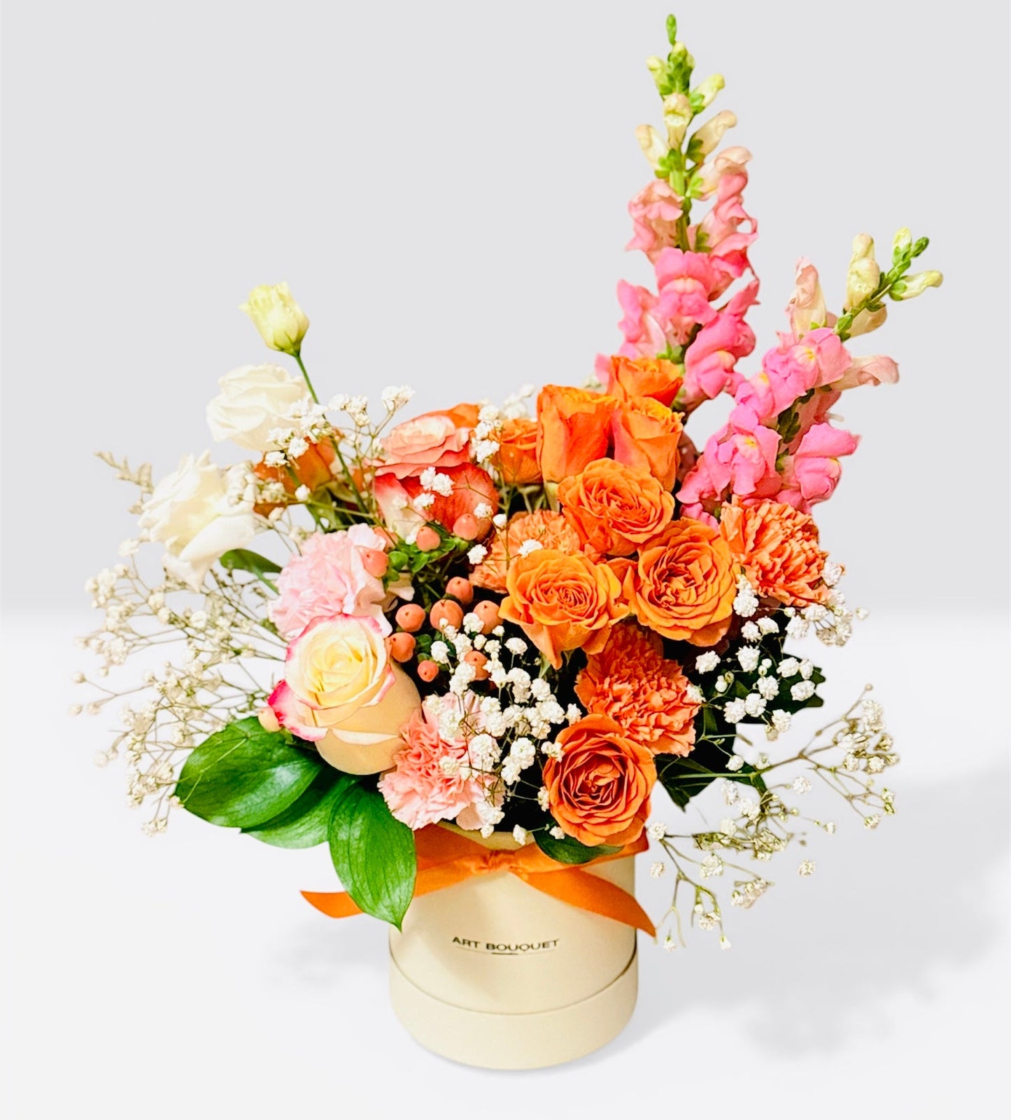 GOLDEN HOUR - orange roses, snapdragons, and carnations hat box arrangement by ART BOUQUET Montreal.  Flowers delivery Montreal.
