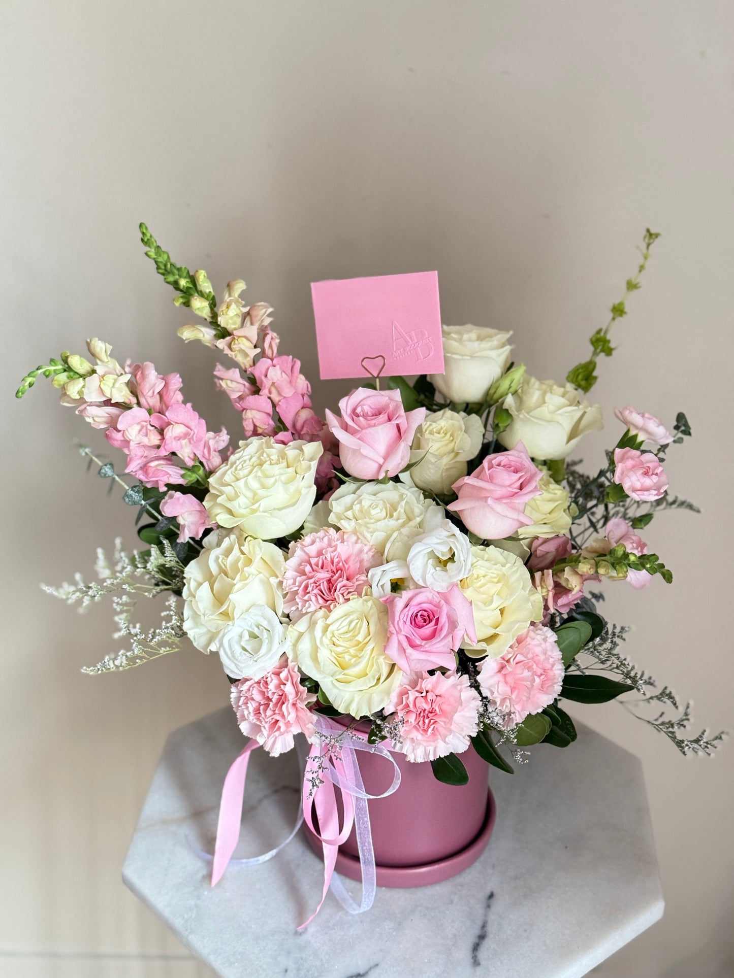 Arrangement Bouquet of pink and white flowers in a pink-purple pot on a marble surface with a light gray background