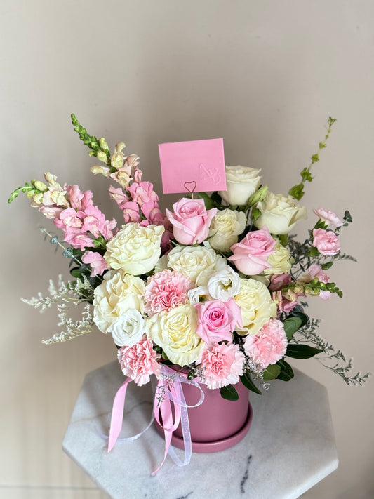 Arrangement Bouquet of pink and white flowers in a pink-purple pot on a marble surface with a light gray background